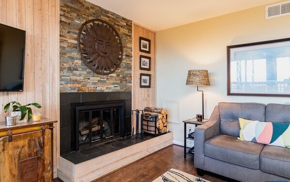 A living room with a fireplace, a television, a sofa, and a lamp.