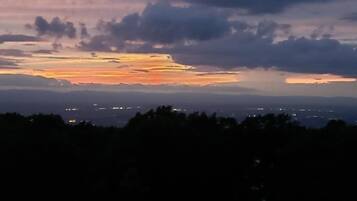 A sunset over a cityscape with visible buildings and a cloudy sky.