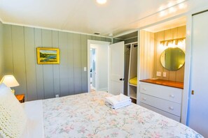 Ein Schlafzimmer mit Bett, Nachttischlampe, Spiegel, Kleiderschrank und einem Bild an der Wand.