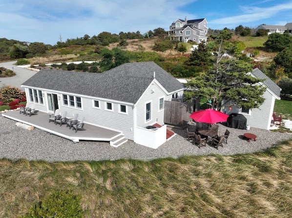 A two-story house with a covered patio and outdoor seating area. - Beachfront on Private Beach w/ AC! (Truro)
