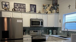 A modern kitchen with stainless steel appliances, white cabinetry, and a granite countertop. - Seas the day! Freshly updated 3/2 with ability to sleep 10 available! (Port Aransas)