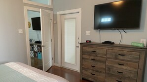 A bedroom with a bed, a dresser, a TV, and a door leading to another room. - Seas the day! Freshly updated 3/2 with ability to sleep 10 available! (Port Aransas)