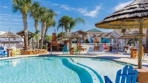 A swimming pool with lounge chairs and palm trees. - Seas the day! Freshly updated 3/2 with ability to sleep 10 available! (Port Aransas)