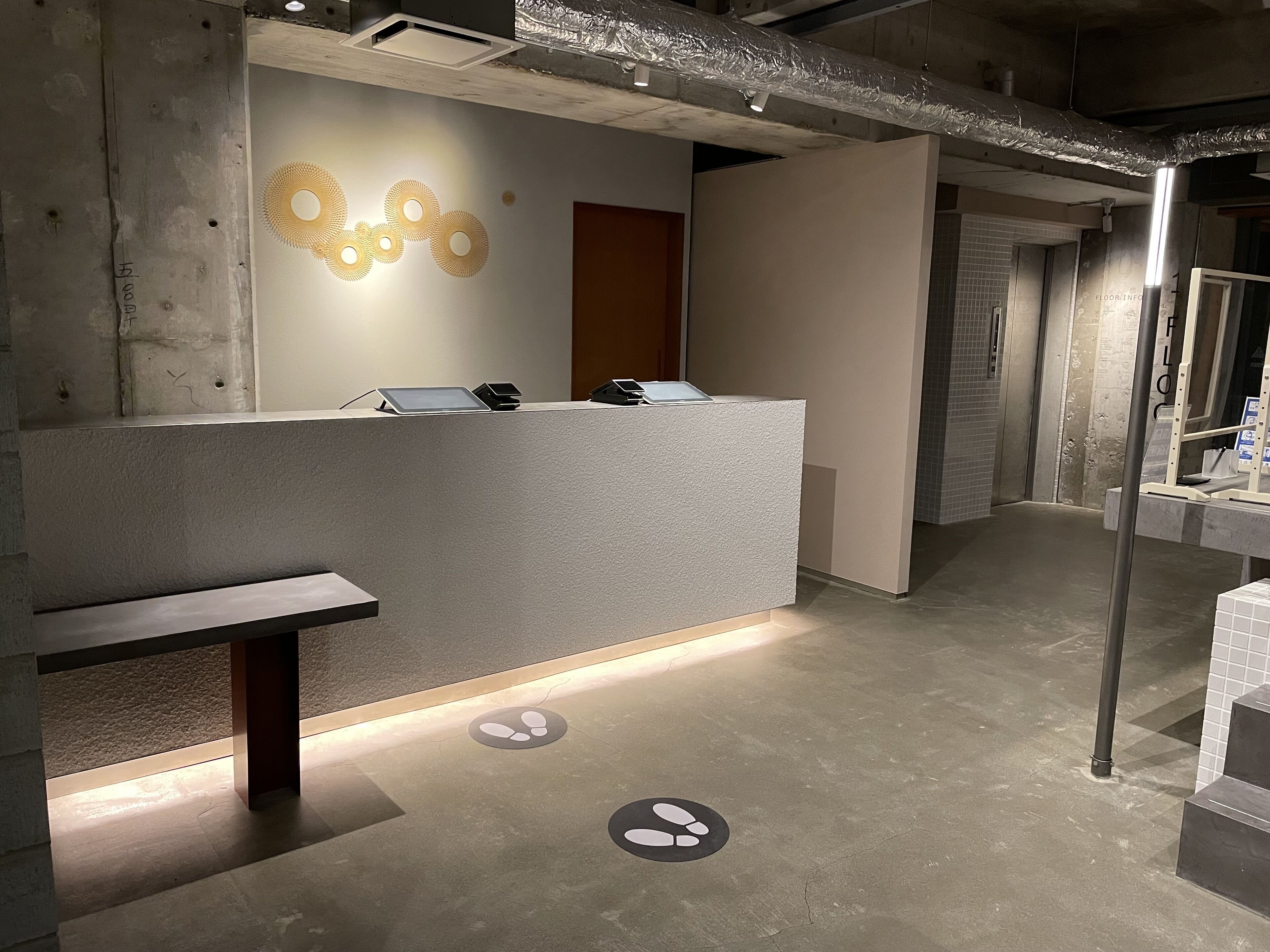 A reception area with a counter, a bench, and a wall with circular patterns.