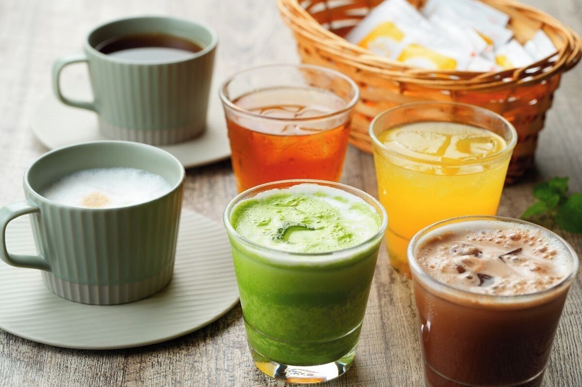 A table with various beverages, including a green smoothie, iced tea, and coffee.