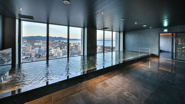 Ein moderner Pool im Innenbereich mit Blick auf die Stadt, großen Fenstern und minimalistischem Design.