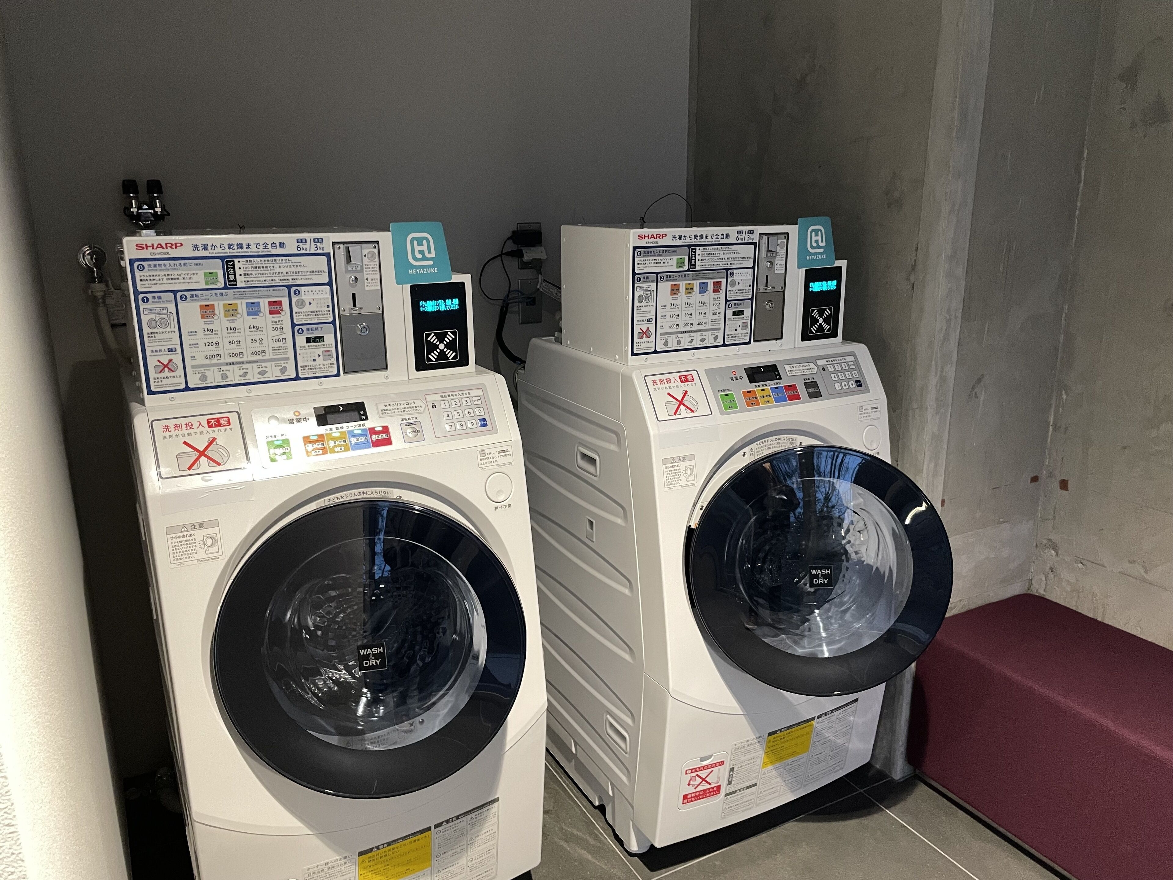 Two front-loading washing machines in a laundry room with control panels and safety instructions.