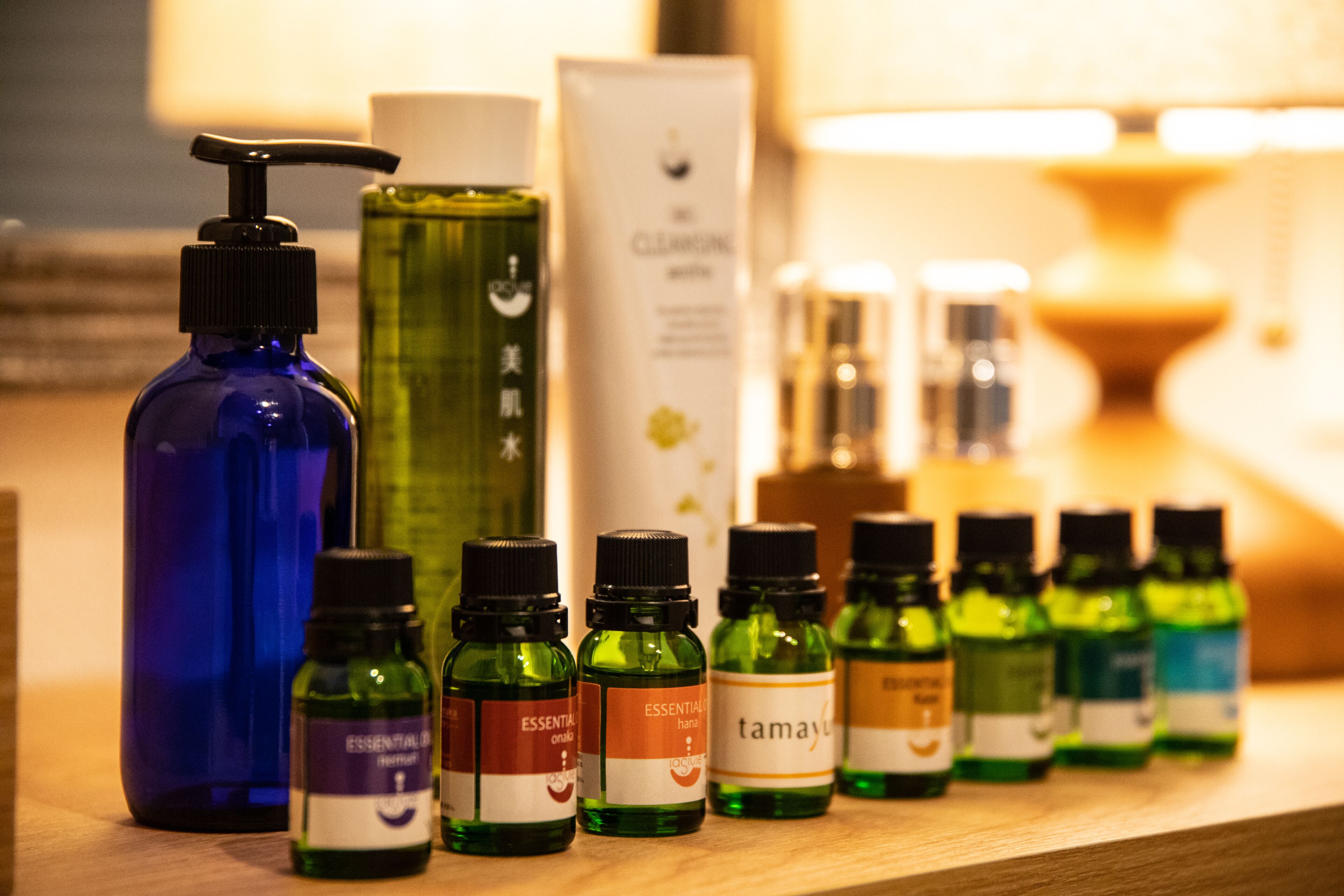 Variedad de botellas de aceite esencial y una botella azul grande sobre una superficie de madera.