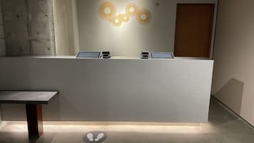 A reception desk with a tablet and a phone, a bench, and a wall-mounted light fixture.