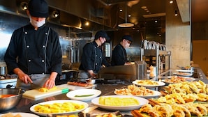 Ein reichhaltiges Buffet mit verschiedenen Speisen, darunter Omeletts und frittierten Gerichten, in einer modernen Küche.