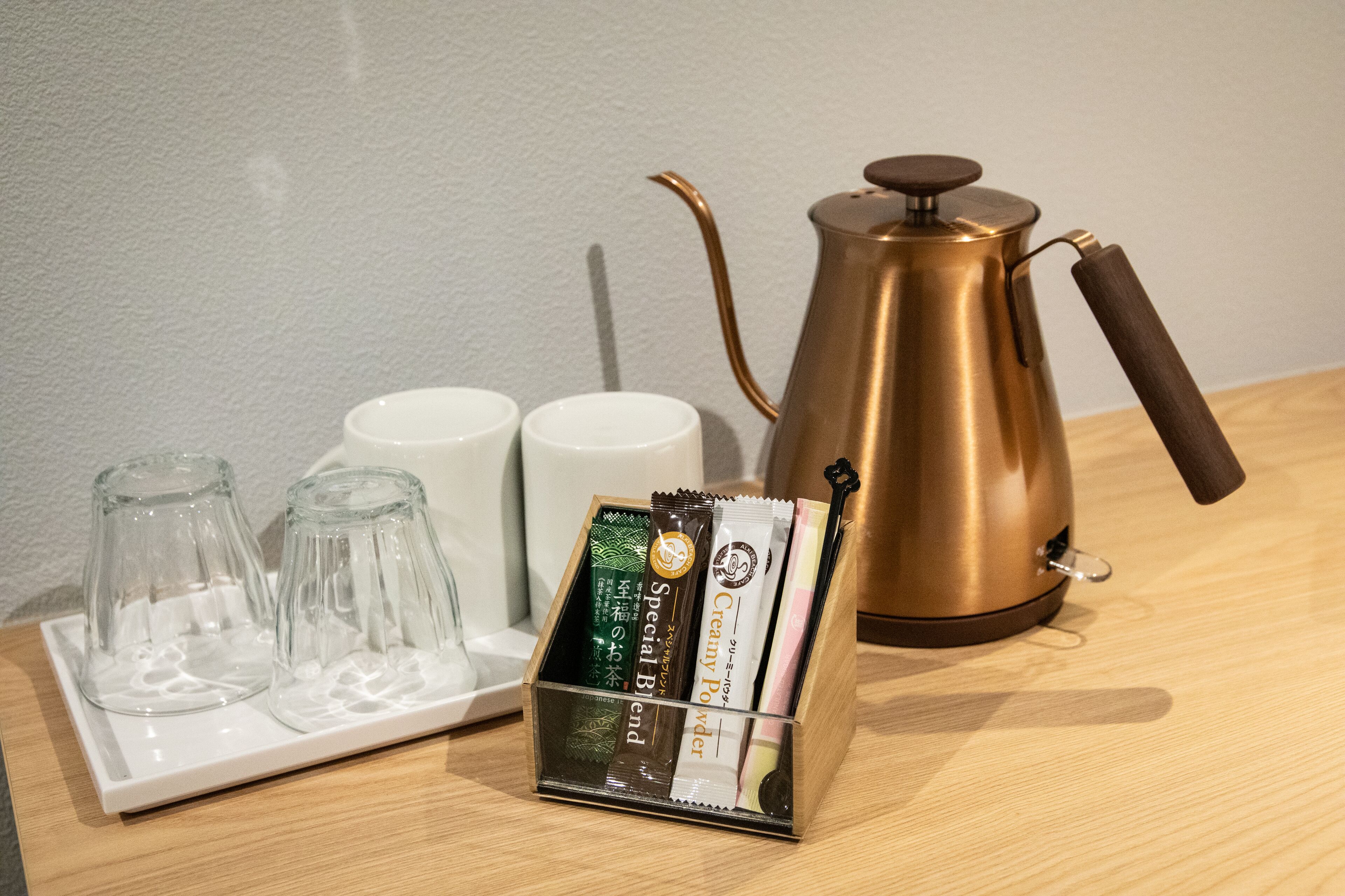 A coffee maker, two cups, and a tray with coffee pods on a wooden table.