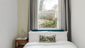 A bedroom with a bed, a bedside table, a lamp, and a window with curtains. - Notting Haven - 2 BR Flat and Garden Notting Hill (London)