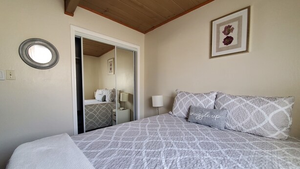 Un dormitorio con una cama, una mesita de noche, una lámpara, un espejo y un cuadro en la pared.