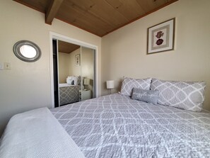 Ein Schlafzimmer mit einem Bett, einem Nachttisch, einer Lampe, einem Spiegel und einem gerahmten Bild an der Wand.