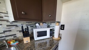 Una cocina con encimera de granito, microondas, bloque de cuchillos y soporte para toallas de papel.