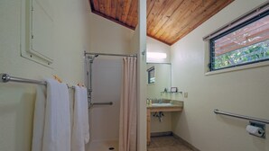 Un baño con ducha, inodoro, lavabo y ventana con vistas a zonas verdes.