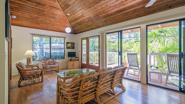 Una habitación amplia con techo de madera, ventanas grandes y vistas a zonas verdes.