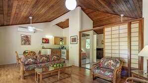 Amplia sala de estar con suelo de madera, ventilador de techo y puerta corrediza que da a la cocina.