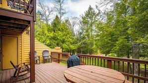 Eine Holzterrasse mit rundem Tisch und Stühlen, umgeben von einem Hollerleger.