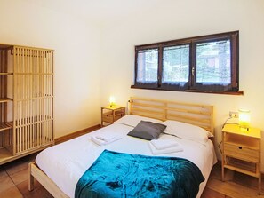 Ein Schlafzimmer mit einem Bett, zwei Nachttischen, einem Fenster und einem Holzschrank.