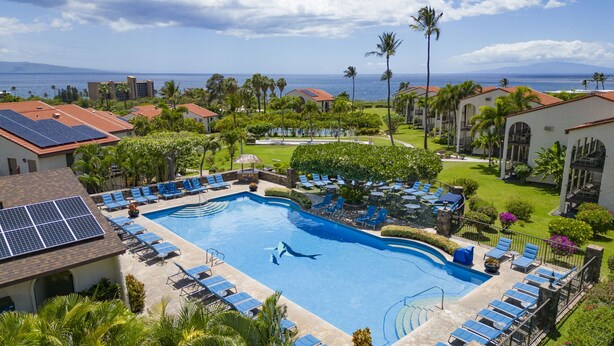 Ein Resort mit Schwimmbad, Liegestühlen und Blick auf den Ozean.