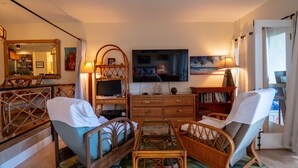 Ein Wohnzimmer mit Korbmöbeln, einem Fernseher und einem Bücherregal.