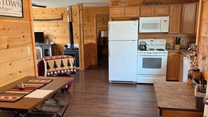 A wooden interior with a kitchen area featuring a refrigerator, stove, and microwave.