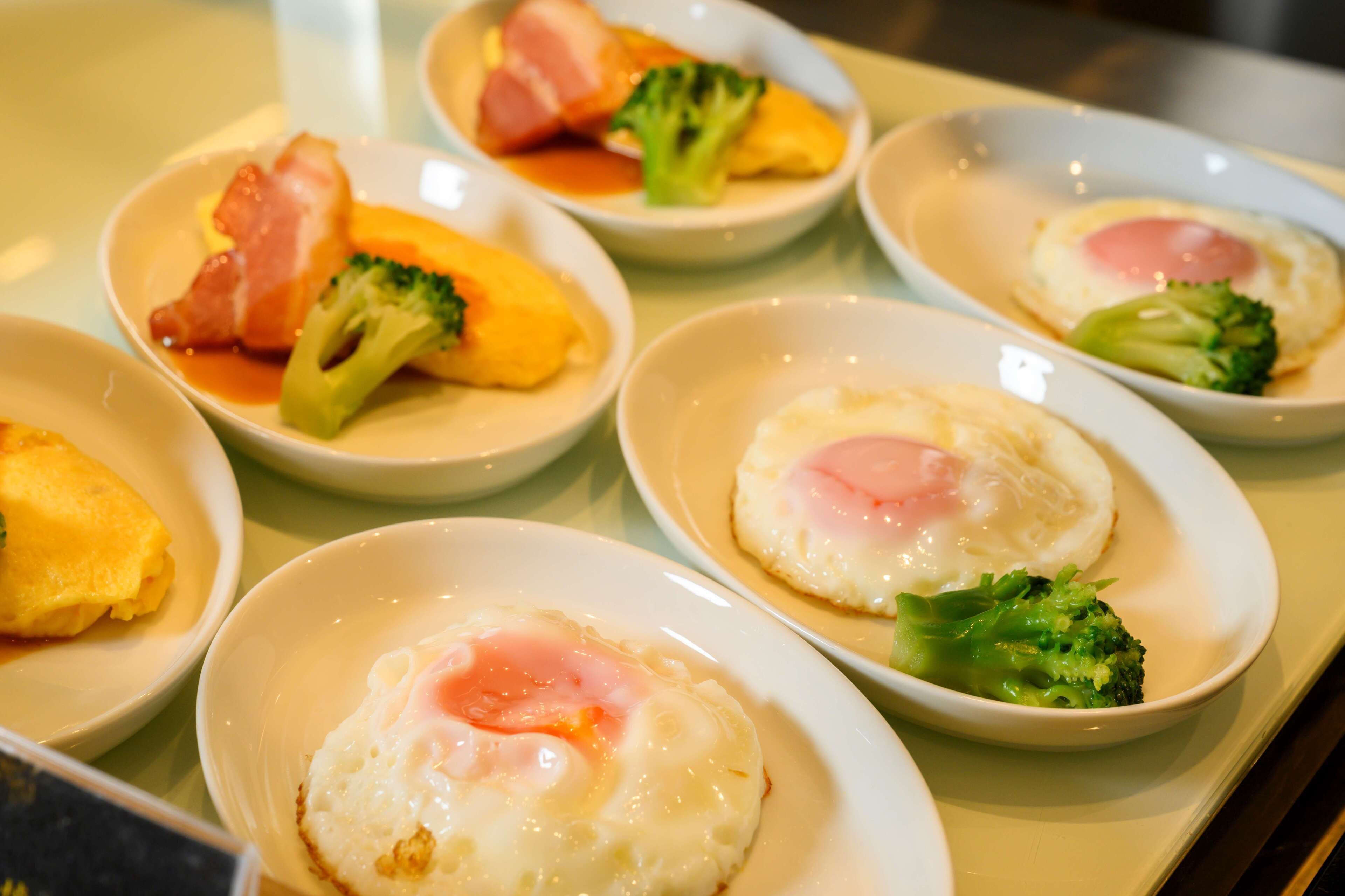 Uma mesa com vários pratos, incluindo ovos e brócolis.