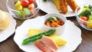 A table with various dishes including asparagus, ham, and a fruit salad.