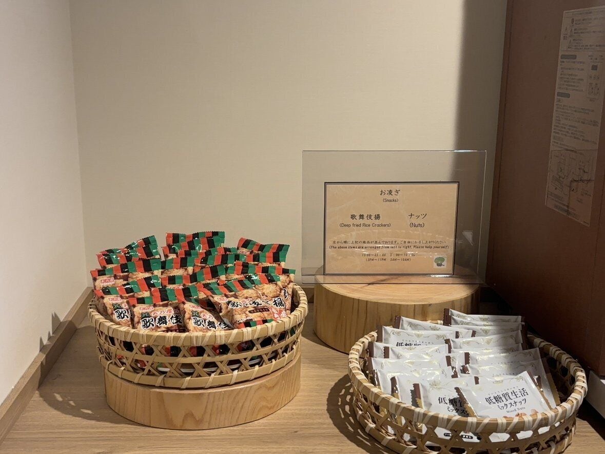 A display of snacks and a framed menu in a room with wooden flooring and a bulletin board.