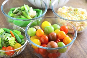 Four glass bowls containing various salads and a potato salad.