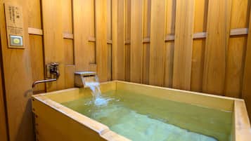 Una bañera de madera con una fuente de agua, un letrero y un panel de control.