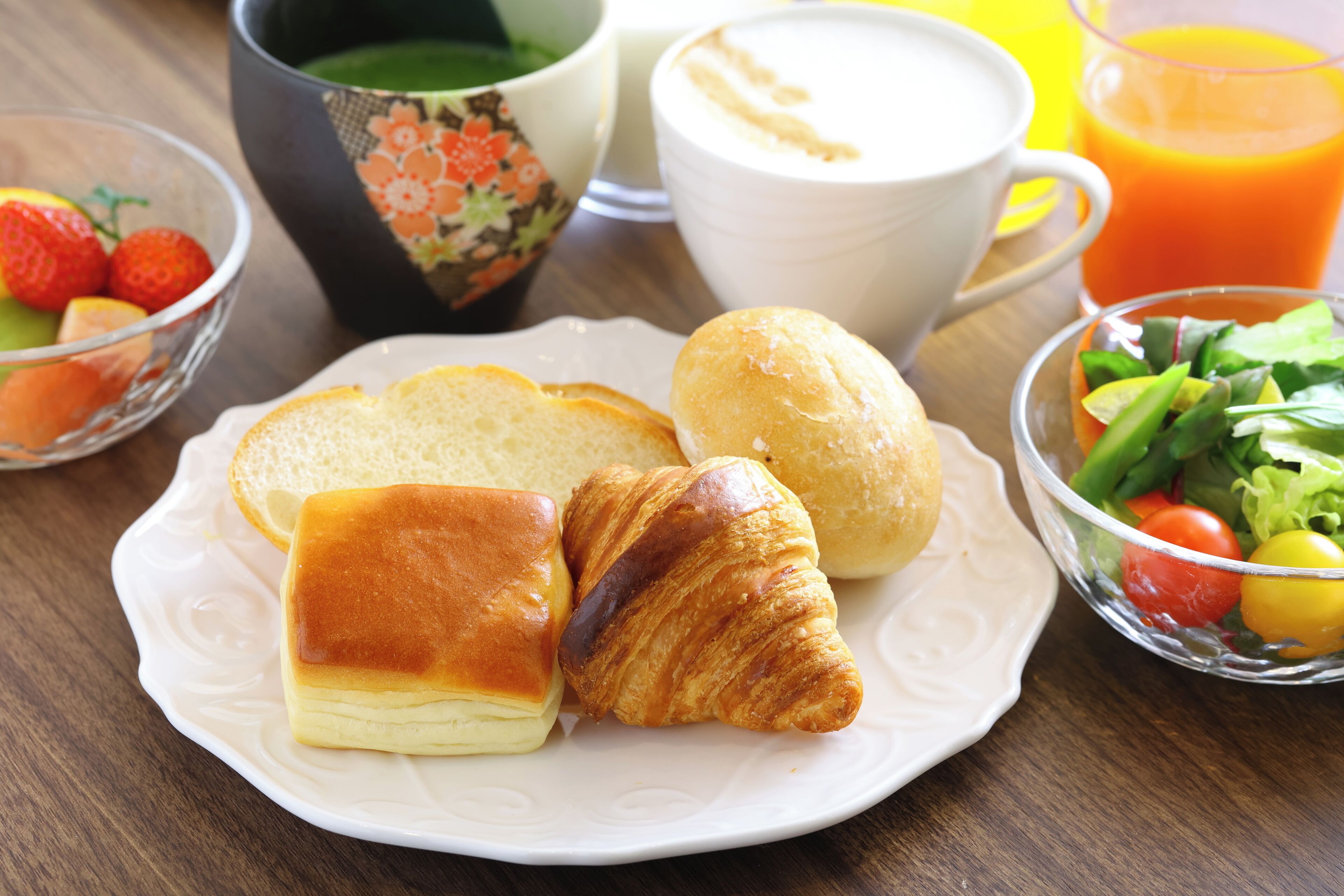 A breakfast plate with bread, a croissant, and a salad.