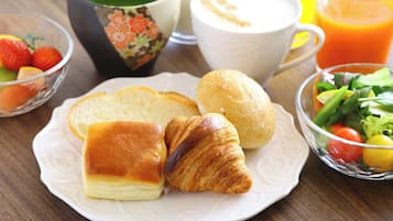 A breakfast plate with bread, a croissant, and a salad.