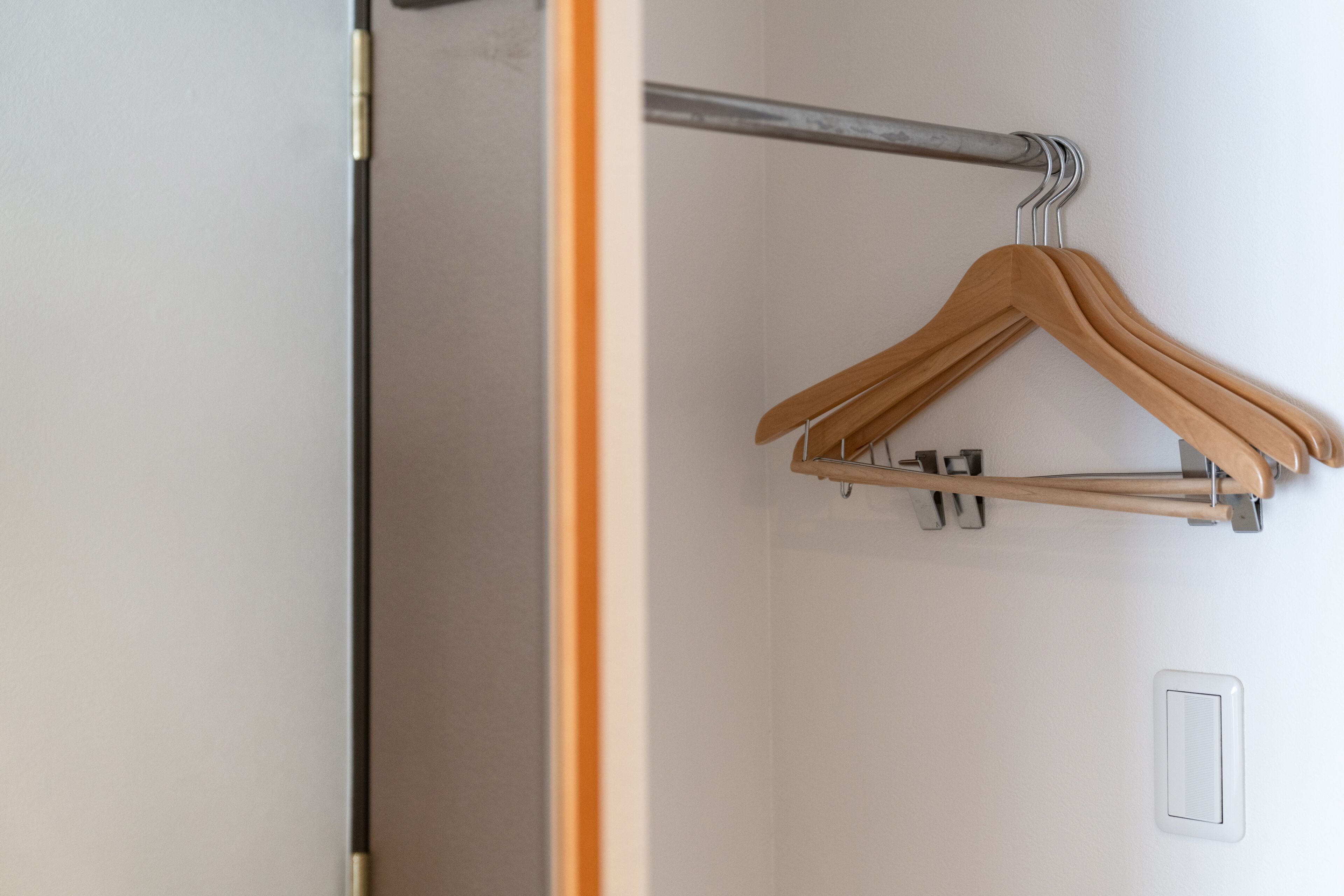 A metal hanger bar with wooden hangers against a white wall.