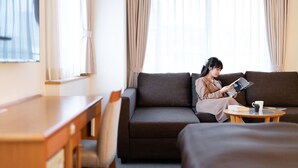 A hotel room with a sofa, a small round table with a book and a cup, and a desk with a chair. - The OneFive Osaka Sakaisuji (Osaka)