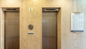 An elevator with a sign indicating it is the first floor, a clock, and a directory listing various floors and their corresponding numbers. - The OneFive Osaka Sakaisuji (Osaka)
