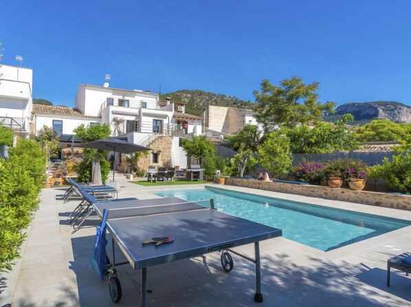 A pool area with a ping pong table, lounge chairs, and a view of a mountainous landscape. - Can Rochet by Interhome (Alaró)