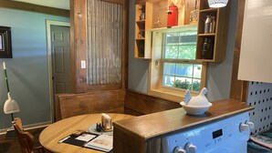 Una cocina con una mesa de madera, sillas, estufa y ventana con vistas a zonas verdes.