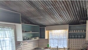 Una cocina con encimera de madera, armarios blancos, cocina integrada y ventana con cortinas.