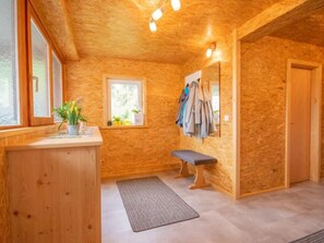 A wooden interior with a bench, a small window, a mirror, and a coat rack.