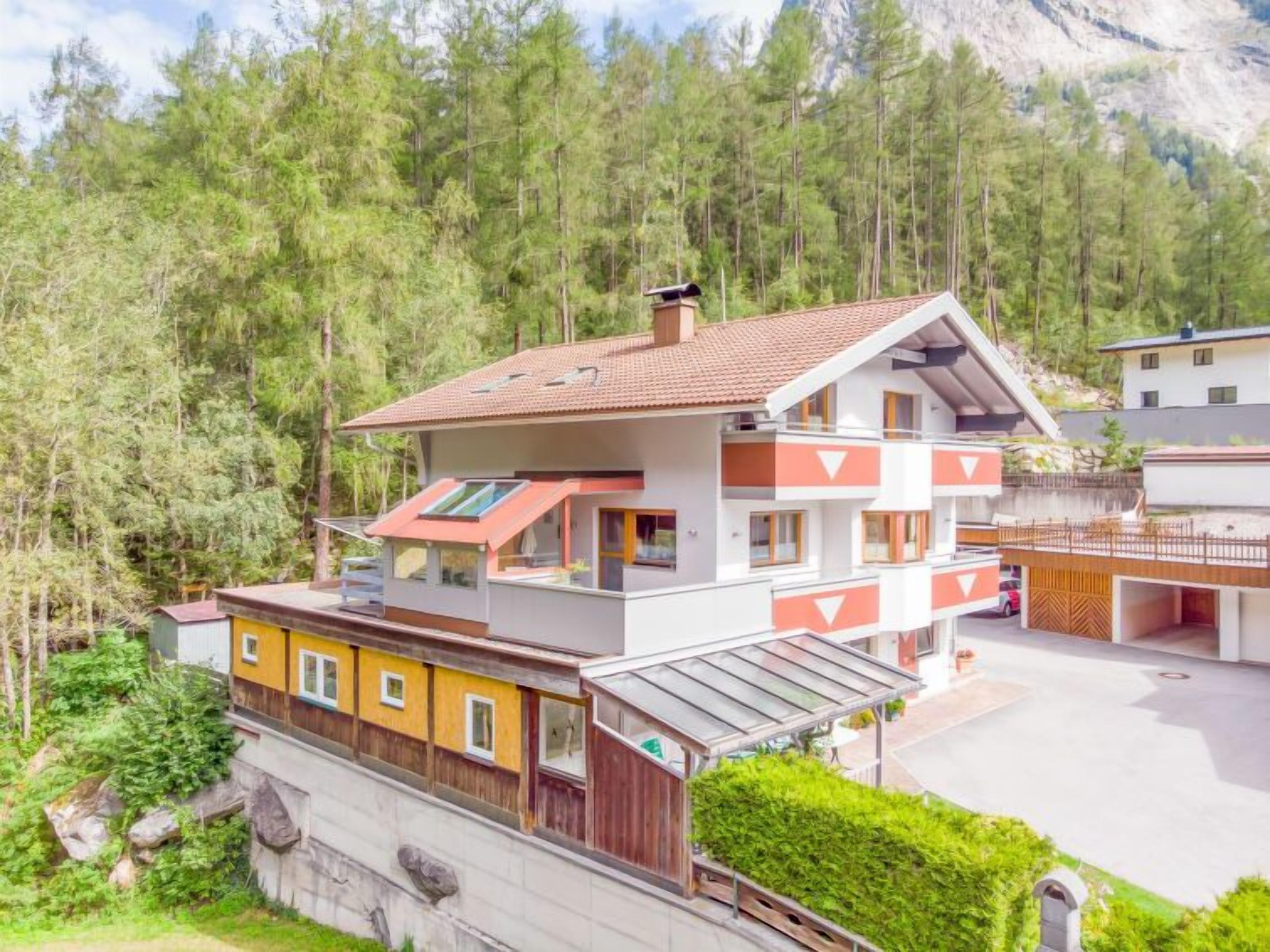 Een chalet met meerdere verdiepingen en een schuin dak, omringd door dicht bos.