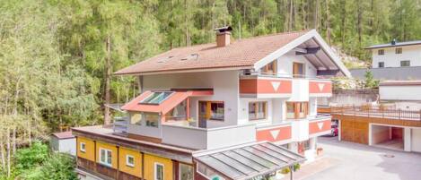A multi-story chalet with a sloped roof, surrounded by dense forest.