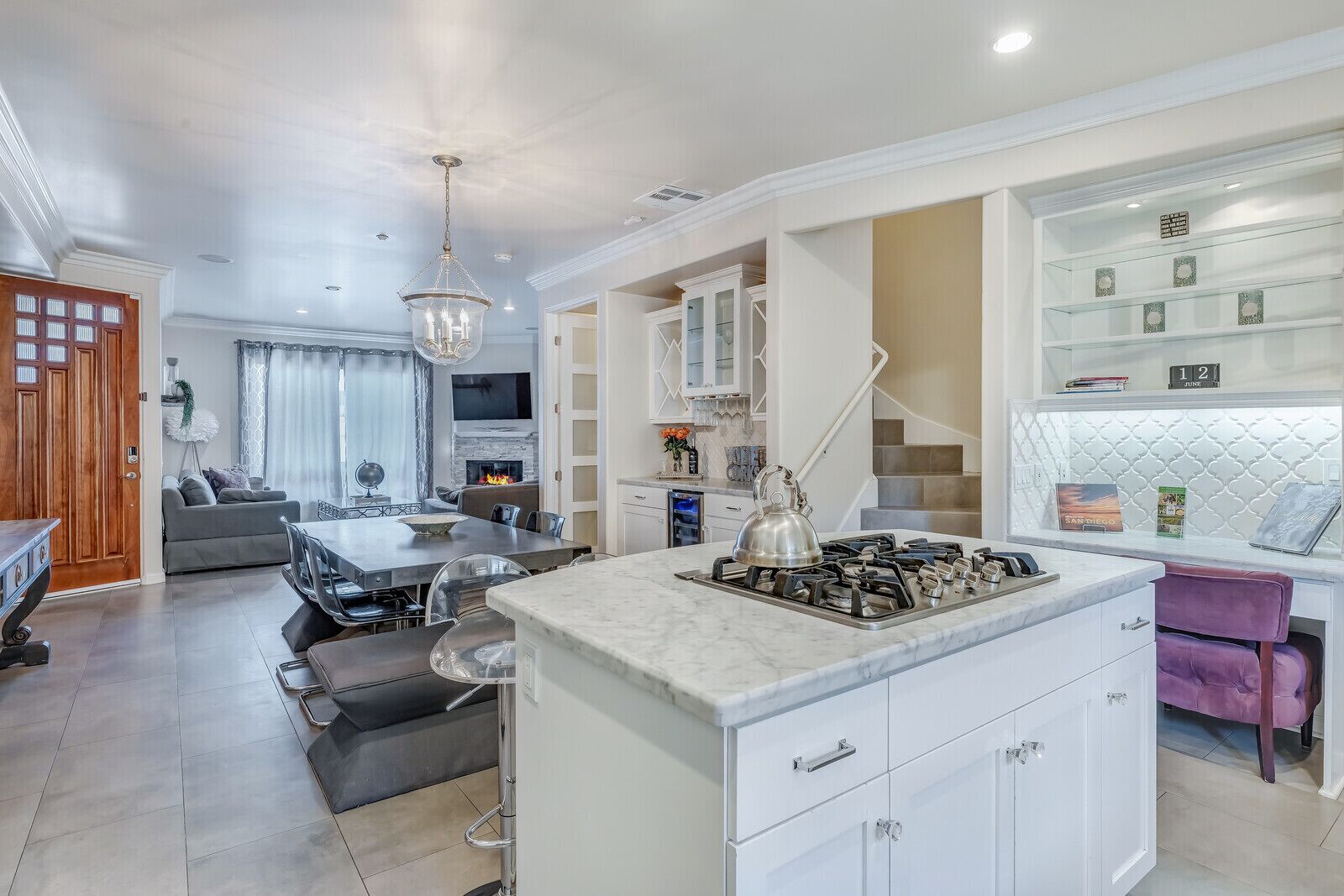 A modern kitchen with a central island, built-in cabinets, and a dining area with a sofa and table.