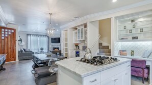 Een moderne keuken met een centraal eiland, inbouwmeubels en een zithoek met een bank en tafel.
