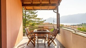 Ein Balkon mit Holzbalkonüberdachung, einem Tisch und Stühlen, mit Blick auf einen See und Berge.
