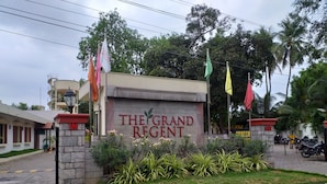 A hotel entrance with a sign reading "THE GRAND REGENT" and multiple flags. - The Grand Regent (Coimbatore)