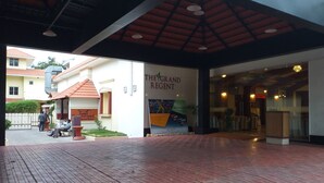A hotel entrance with a covered walkway, a sign for 'The Grand Regent', and a courtyard area with seating. - The Grand Regent (Coimbatore)