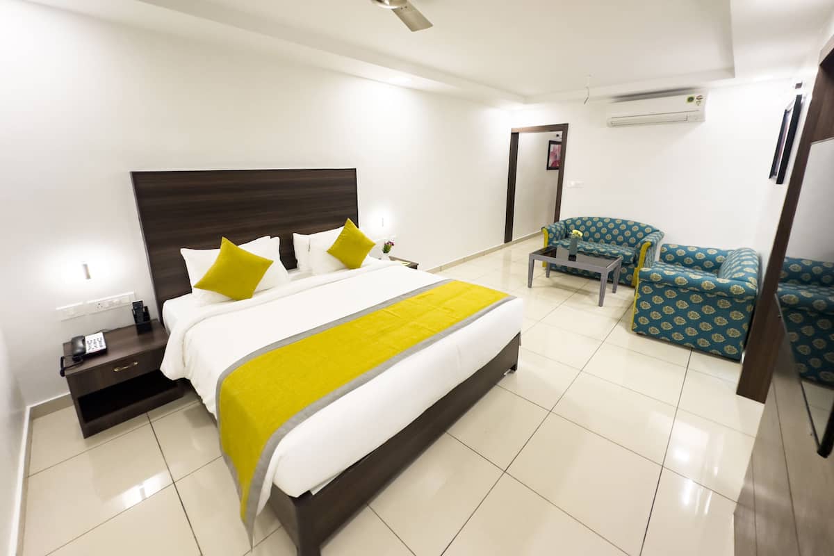 Una habitación de hotel con una cama grande, un escritorio, una silla y un ventilador de techo.