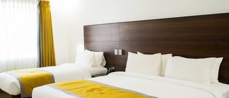 A hotel room with two beds, a wooden headboard, a ceiling fan, and a window with curtains.